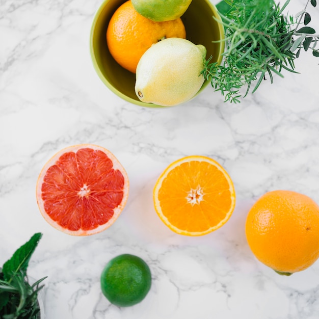 Different type of citrus fruits and rosemary on marble