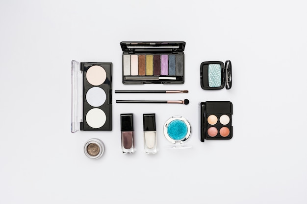 Different type of cosmetics palette with makeup brushes on white background