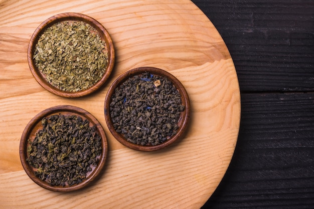 Different type of dried tea leaves on wooden table