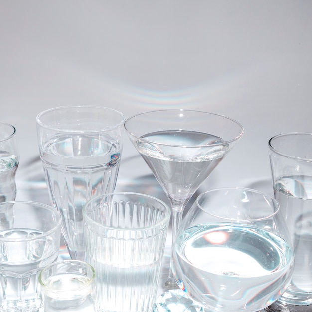 Different type of glasses with liquid against gray backdrop