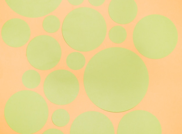 Different type of green paper circles on an orange backdrop