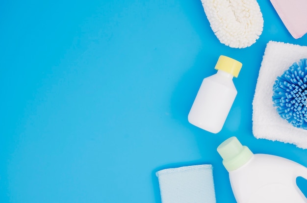 Different type of sponges with detergent bottles on blue backdrop