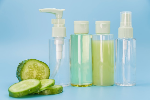 Different type of spray bottles with cucumber slices on blue background