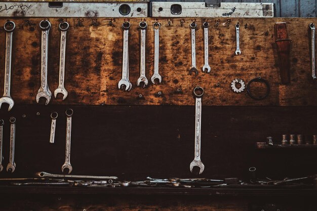 Different type of tools, especially wrenches, are hanging on the wall at workshop.