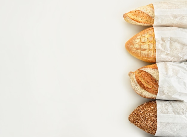 Different types of bread in paper bags on a white background. top view.