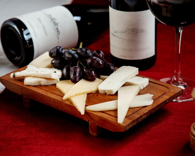 Different types of cheeses and grapes on a wooden board