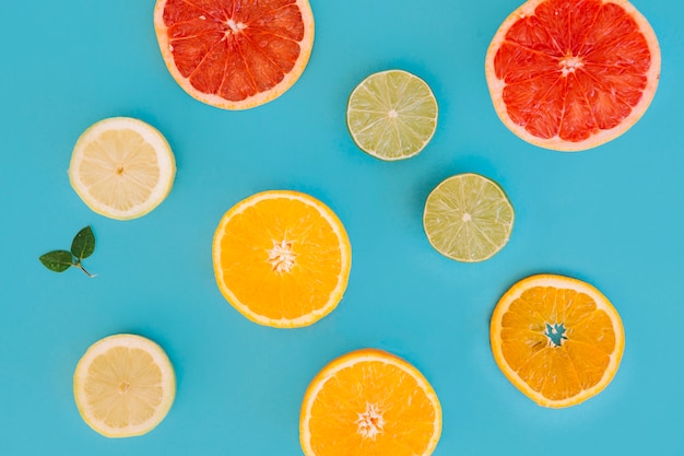 Different types of citrus fruits slices on blue backdrop