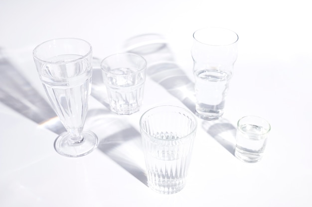 Different types of glasses with shadow on white backdrop