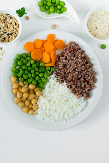 Different types of porridge with vegetables on big plate with rice bowls