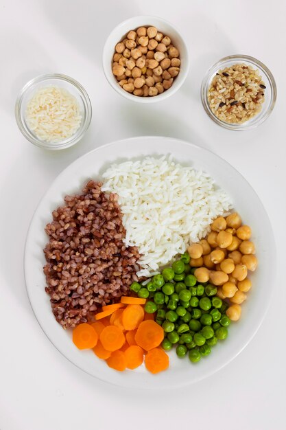 Different types of porridge with vegetables on plate with rice bowls 