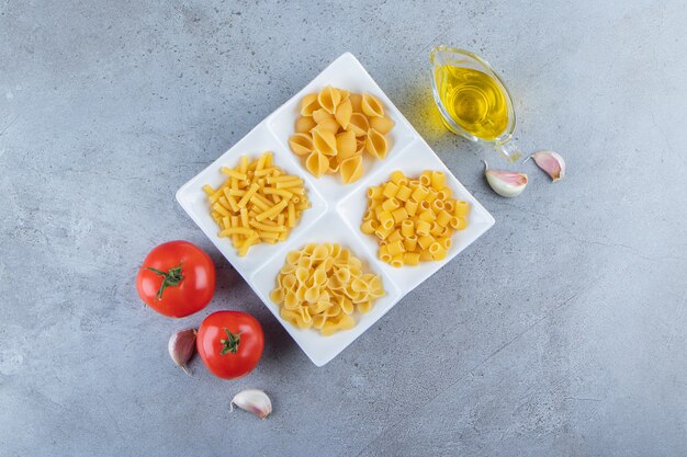 Different types of raw dry pasta on a stone background.