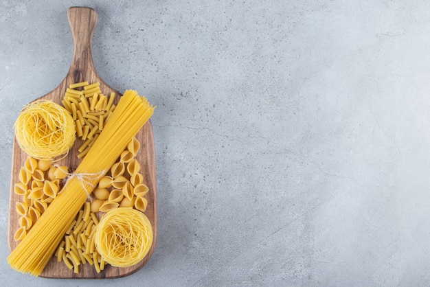 Different types of raw dry pasta on a stone background. 