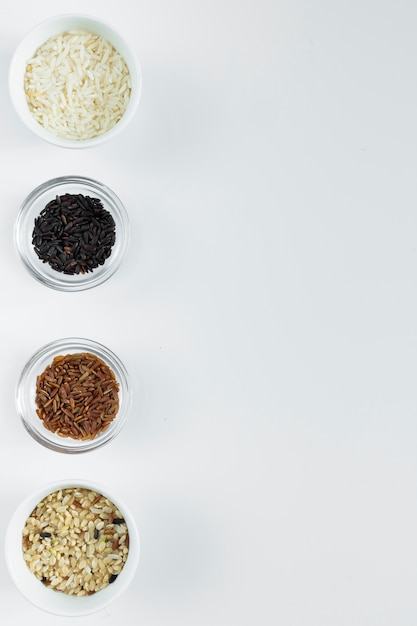 Diversi tipi di riso in ciotole sul tavolo bianco