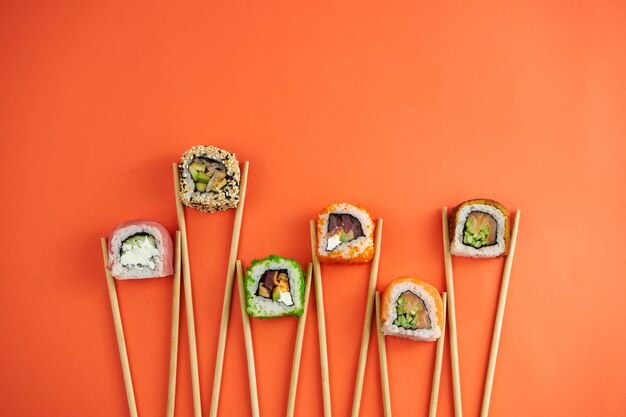 Different types of sushi rolls with tuna, eel, salmon. mockup with chopsticki and sushi on orange background