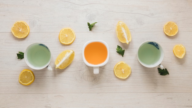 Different types of tea in ceramic cup with leaves and lemon slices on wooden table