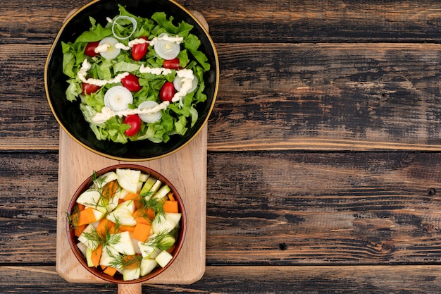 Free photo different vegetable salad on cutting board top view wooden table