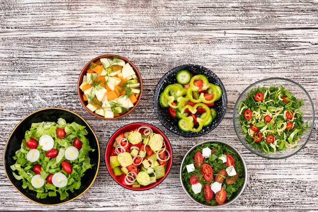 different vegetable salads in bowls on wooden table