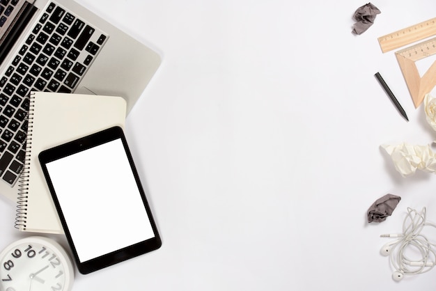 Digital tablet; laptop; alarm clock and office supplies on white background