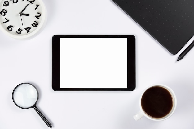 무료 사진 자명종을 가진 디지털 태블릿; 확대경; 커피 컵과 흰색 배경에 스타일러스와 그래픽 디지털 태블릿