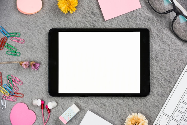 Free Photo digital tablet with white screen display surrounded with office supplies on gray backdrop