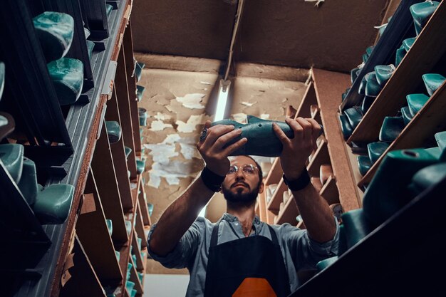 Diligent cobbler is find a right shoe form for his new project at the storage.