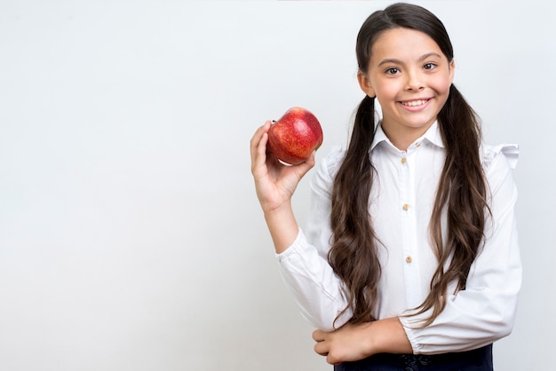 Diligent Hispanic schoolgirl eating apple