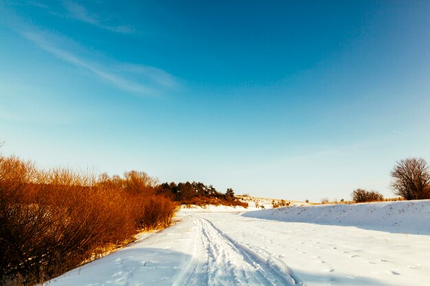 Diminishing perspective ski track on snowy landscape against blue sky