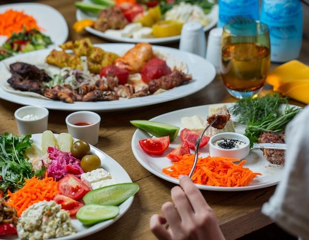 Dinner set in white plates containing meat and vegetables, snacks foods.