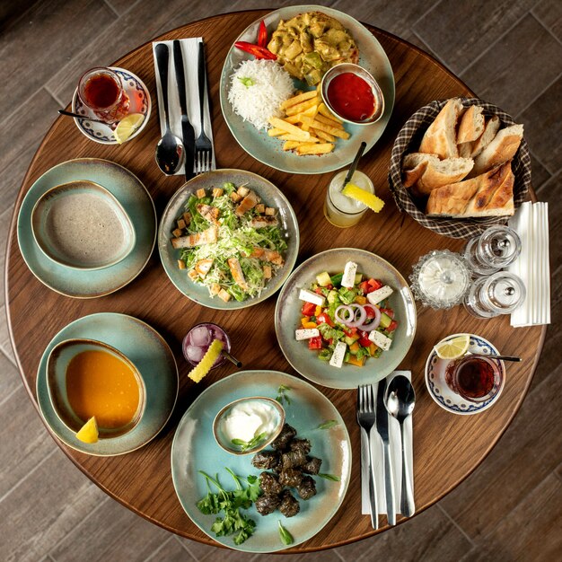 Dinner set with dolma soups, salads and chicken with rice and french fries