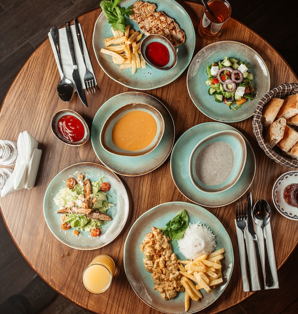 Free photo dinner set with mushroom and lentil soups, salads and chicken with french fries and rice