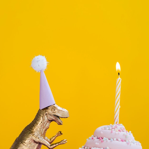 Бесплатное фото Динозавр со шляпой на день рождения и вкусным кексом