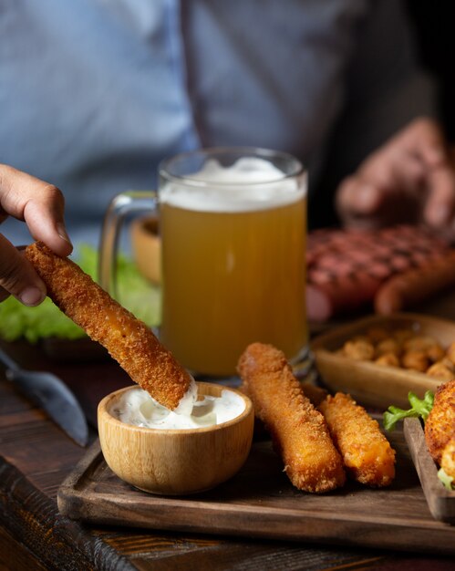 Dipping chicken nugget sticks into mayonnaise.