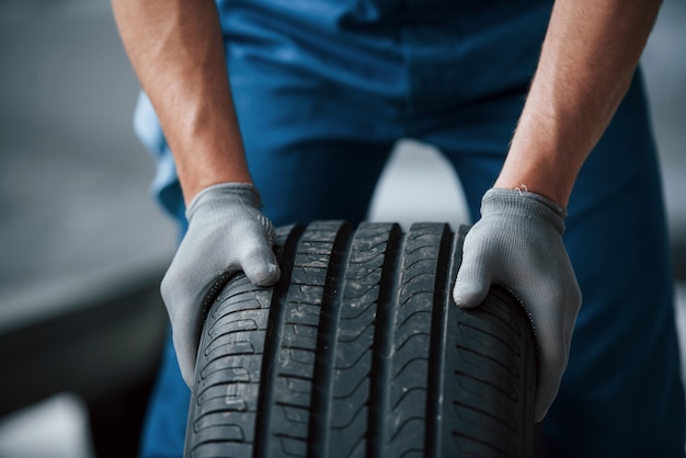 Dirt on the wheel. Mechanic holding a tire at the repair garage. Replacement of winter and summer tires