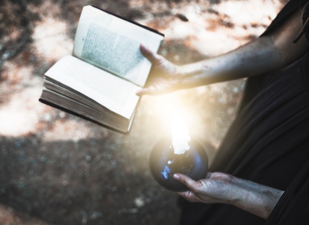 Foto gratuita mani sporche che tengono il volume e la candela rituali