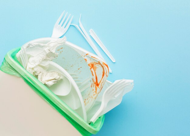 dirty white cutlery and plates in bin