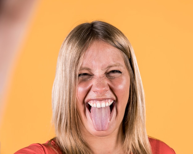 Free photo disable woman sticking out her tongue against plain surface