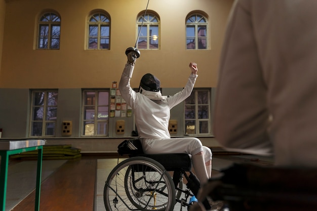 휠체어에 앉아 있는 특수 장비의 장애인 검객