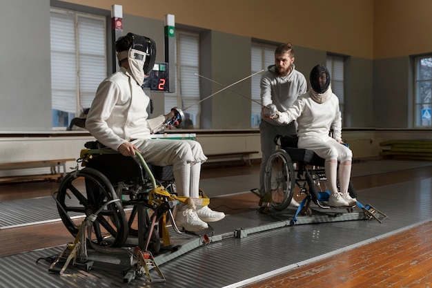 Schermitori disabili in attrezzatura speciale che combattono dalle loro sedie a rotelle Foto Gratuite