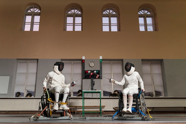 Free photo disabled fencers in special equipment fighting from their wheelchairs