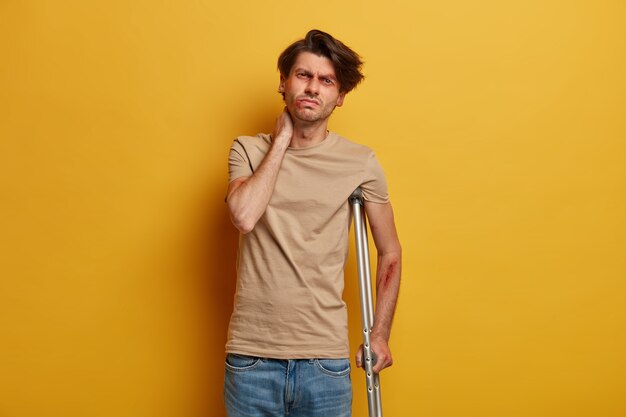 Disabled frustrated man touches neck, has problems with spine