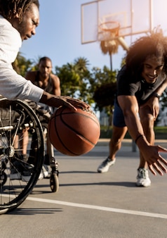 야외에서 친구들과 농구를 하는 휠체어를 탄 장애인
