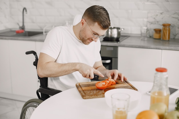 Disabled Man Preparing Food In Kitchen. Cutting vegetables.