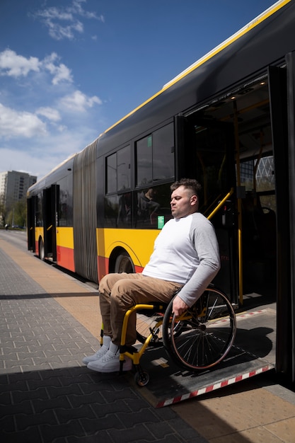 バスのフルショットを待っている障害者の男
