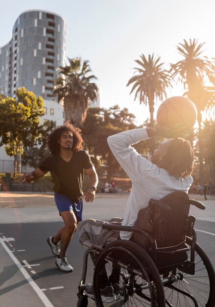 屋外で彼の友人とバスケットボールをしている車椅子の障害者の男性
