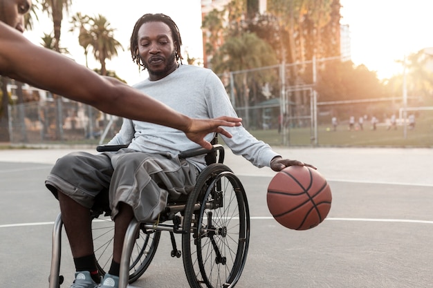 Человек-инвалид в инвалидной коляске играет в баскетбол со своими друзьями