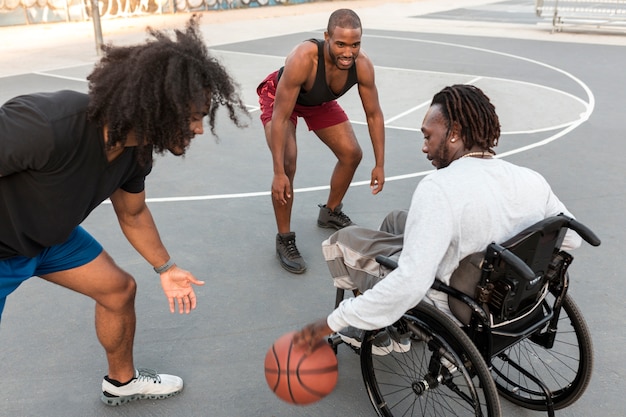 Disabled man in wheelchair playing basketball with his friends