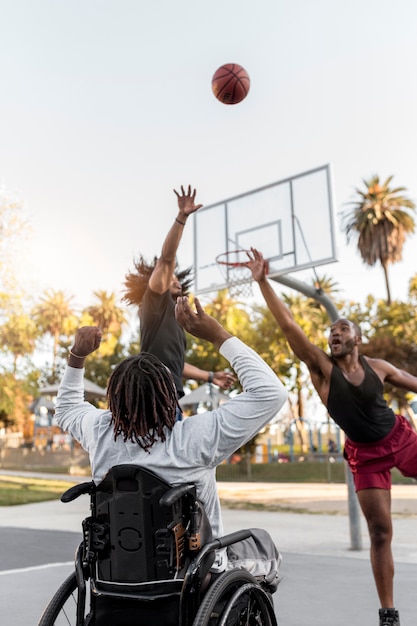 Disabled man in wheelchair playing basketball with people