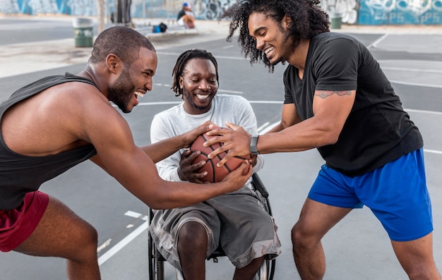 Uomo disabile in sedia a rotelle che gioca a basket con le persone