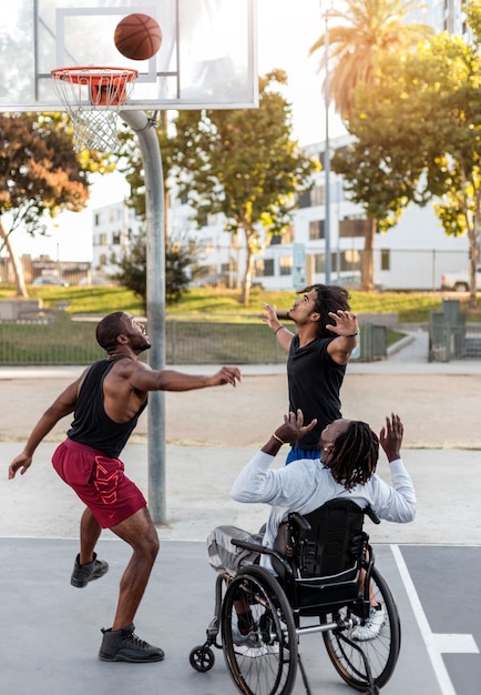 Disabled man in wheelchair playing basketball with people