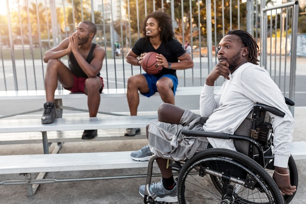 Disabled man in wheelchair with his friends on a basketball field